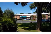 Exterior view of Woodhaven HFA facility with brick building, parking lot, and trees.