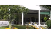 Covered front entrance of a nursing facility with white columns, a porch, steps, and surrounding landscaping.