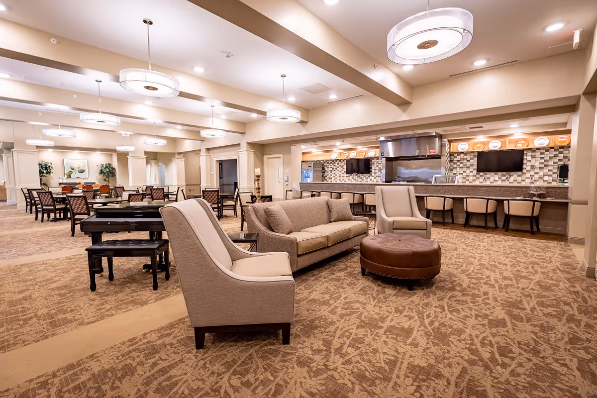 Spacious communal dining and lounge area with sofas, armchairs, dining tables, and a serving counter.