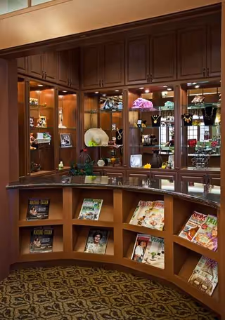 Curved wooden reception counter with glass-front cabinets and magazines.