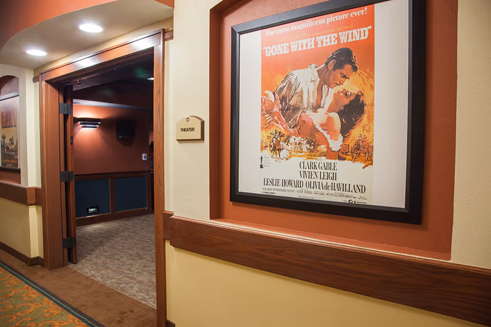 Hallway interior with a framed 'Gone With The Wind' poster and an open door leading into a small theater room.