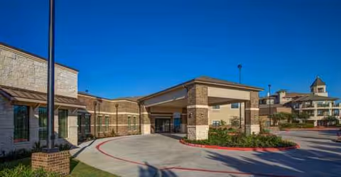 Exterior view of Atria Cinco Ranch with a covered entrance and circular driveway.