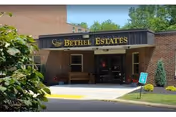 Front entrance of Bethel Estates showing a covered brick portico with the facility sign above the doorway.