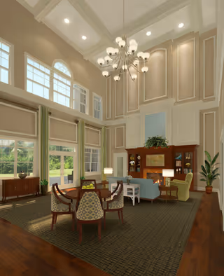 A spacious and elegant living room with high ceilings and large windows allowing natural light to fill the space. The room features a chandelier, a fireplace with a wooden mantel, a blue sofa, a green armchair, a round wooden table with four patterned chairs, and various plants and lamps. The walls are decorated with panel molding and a large painting above the fireplace.