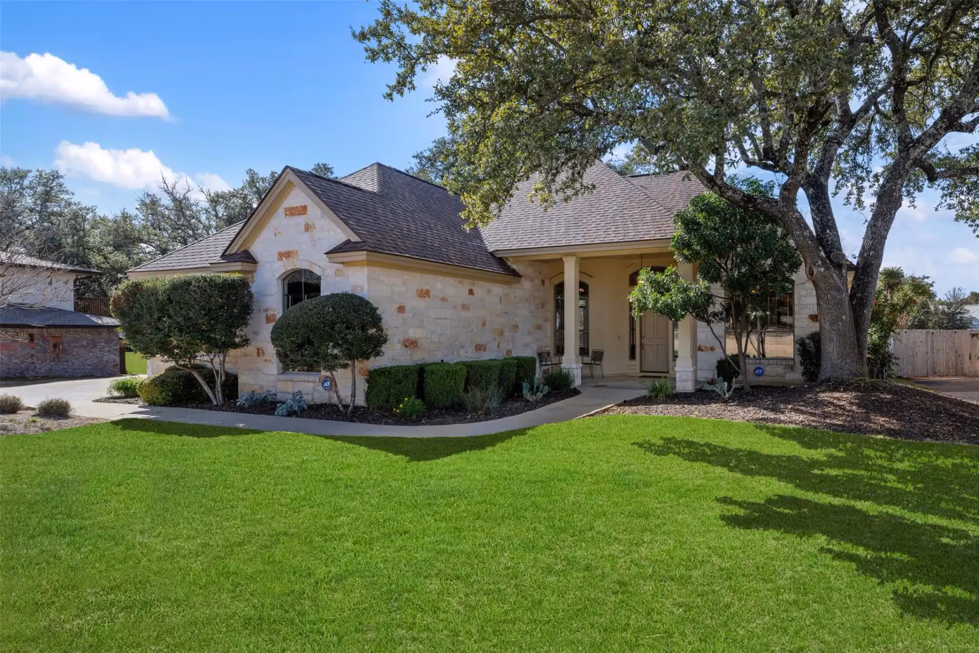 Single-story stone facility with front entrance, trimmed shrubs, and a lush green lawn.