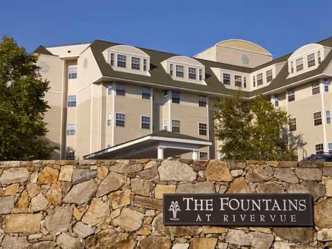 Exterior view of The Fountains at RiverVue building behind a stone wall sign.