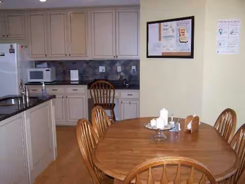 Dining area with wooden table and chairs, adjacent to a kitchen with cabinets.