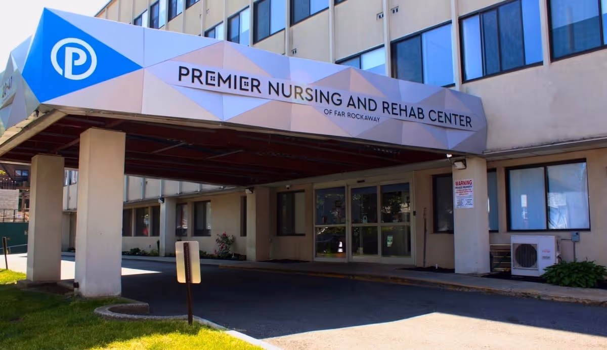 Covered entrance and front facade of Premier Nursing and Rehab Center of Far Rockaway with prominent signage.