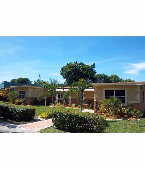 Single-story adult living facility with beige exterior and landscaped front yard.