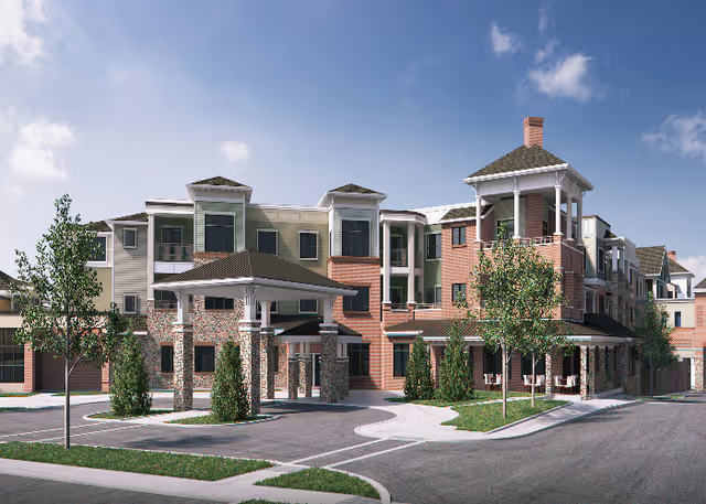 Front exterior of a multi-story senior living building with a covered entrance, balconies, and landscaped driveway under a blue sky.