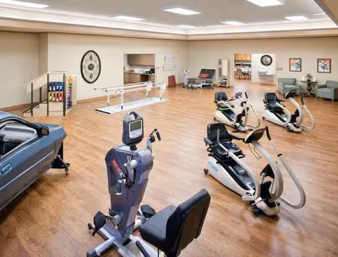 Spacious rehab gym with exercise bikes and ellipticals in a senior facility.