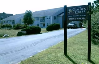 Exterior view of The Golden Crest senior living facility with a driveway and sign.