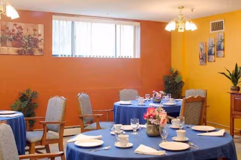 Bright dining room with blue tablecloths, chairs, and floral centerpieces.