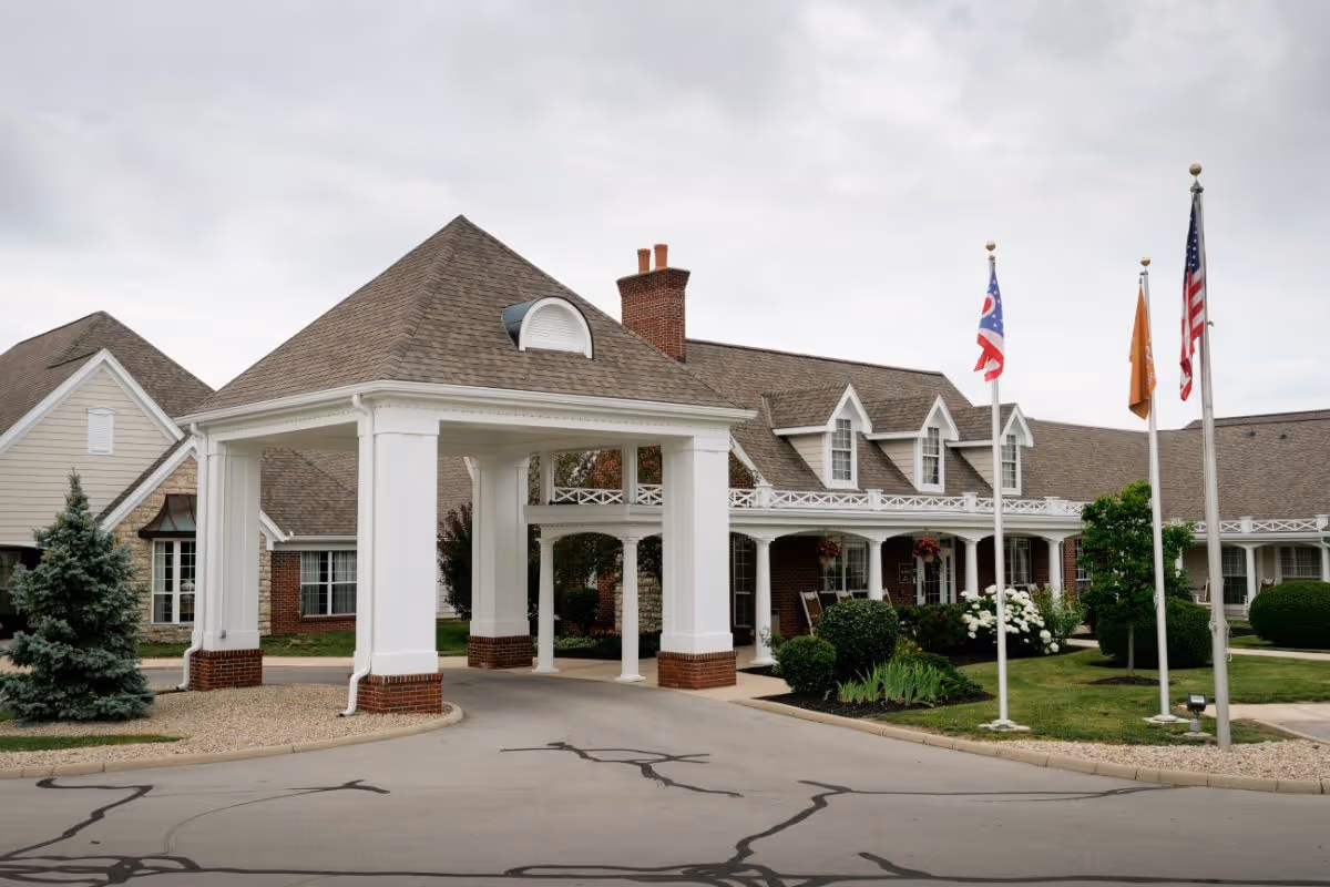 Front entrance of Sunrise of Findlay showing a covered porte-cochere, flagpoles, and landscaped grounds.