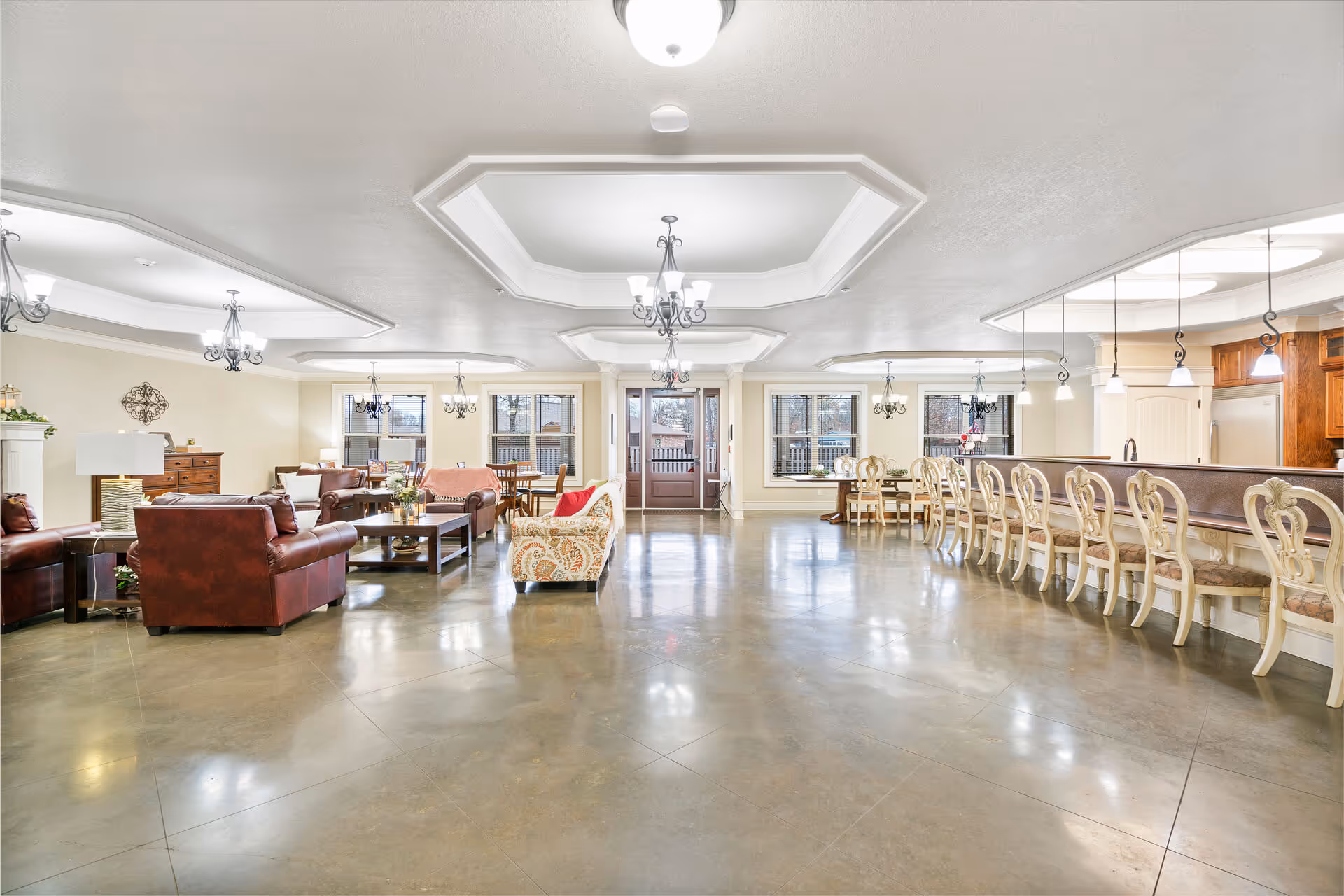 Spacious communal lounge and dining area with sofas, chairs, coffee tables, and a long counter with bar stools.