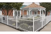 Front exterior of a brick senior living facility with a white metal fence and a gazebo-style porch.
