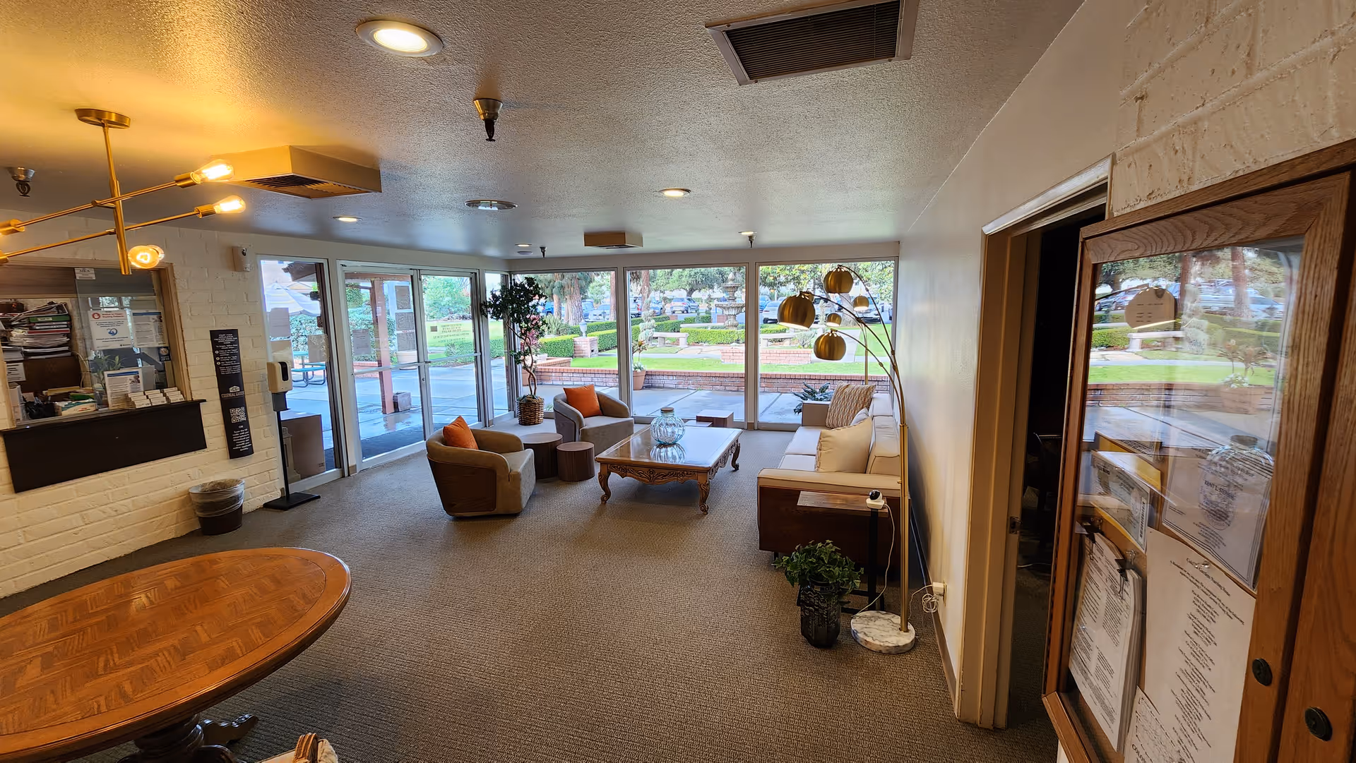 Well-lit lobby/lounge with sofas, chairs, a coffee table and large windows overlooking a courtyard.
