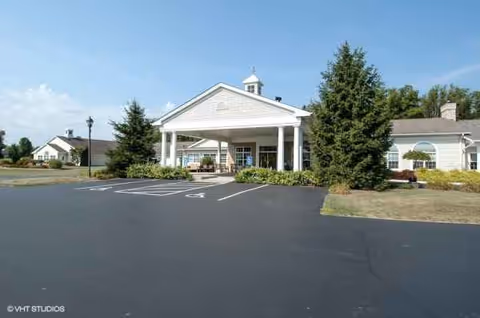 Front view of Whispering Pines Village entrance with a covered porte-cochere and parking.