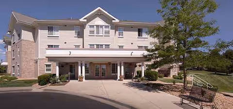 Front view of a beige senior living facility with a covered entrance.