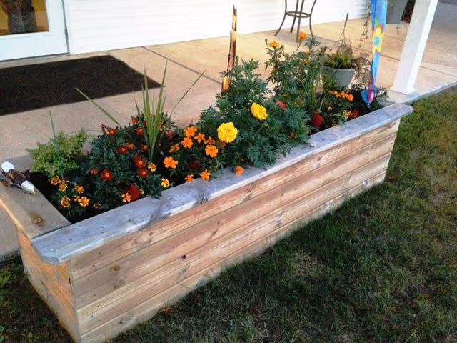 A wooden raised planter with colorful flowers sits outside VitaCare Living Hayward.
