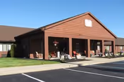 Exterior view of Oakbrook Village facility showing entrance, parking lot, and planters.