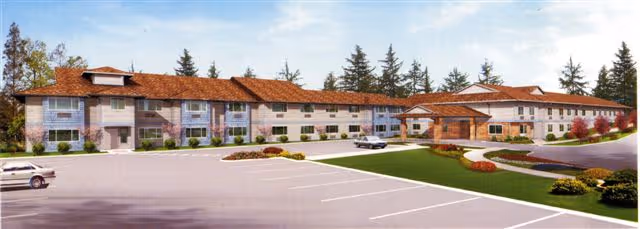 Exterior view of Chehalis West Assisted Living facility showing a two-story building with a red-tiled roof, multiple windows, and a covered entrance. The foreground features a large parking lot with a few cars and landscaped areas with grass, bushes, and trees.