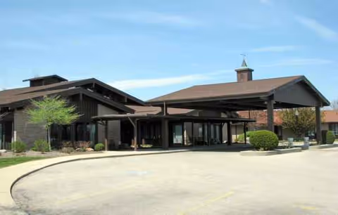 Exterior view of Swiss Village Retirement Community building with a covered entrance and circular driveway.