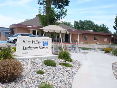Exterior view of Blue Valley Lutheran Homes Nursing Home with sign, landscaped rocks, and building.