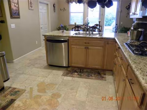 Bright kitchen in a care home with island, sink, and wooden cabinets.