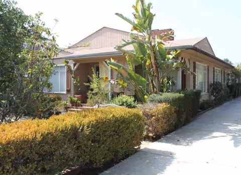 VIP Guesthome exterior with hedge-lined walkway and tropical plants.