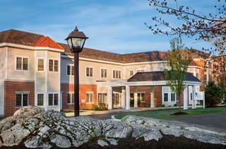 Exterior view of The Cedars senior living facility with a brick facade and entrance.