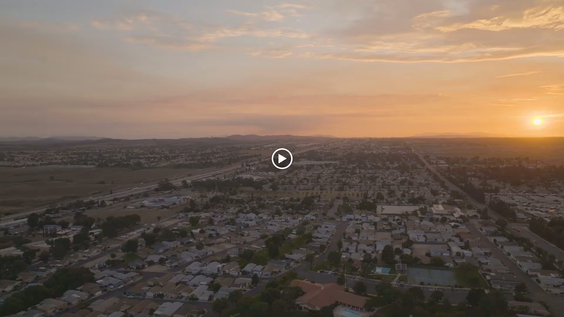 Aerial view of a suburban neighborhood at sunset with the sun low on the horizon.