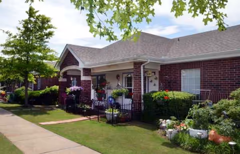 Exterior view of Village on the Park Oklahoma City entrance with brick facade and landscaped yard.