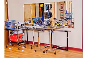 A rehabilitation room with parallel bars for physical therapy, a mirror on the wall, and various therapy equipment including baskets and weights on a wooden floor.