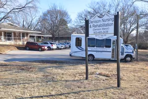 Exterior view of Denison Nursing & Rehab with a bus and parked cars in the lot.