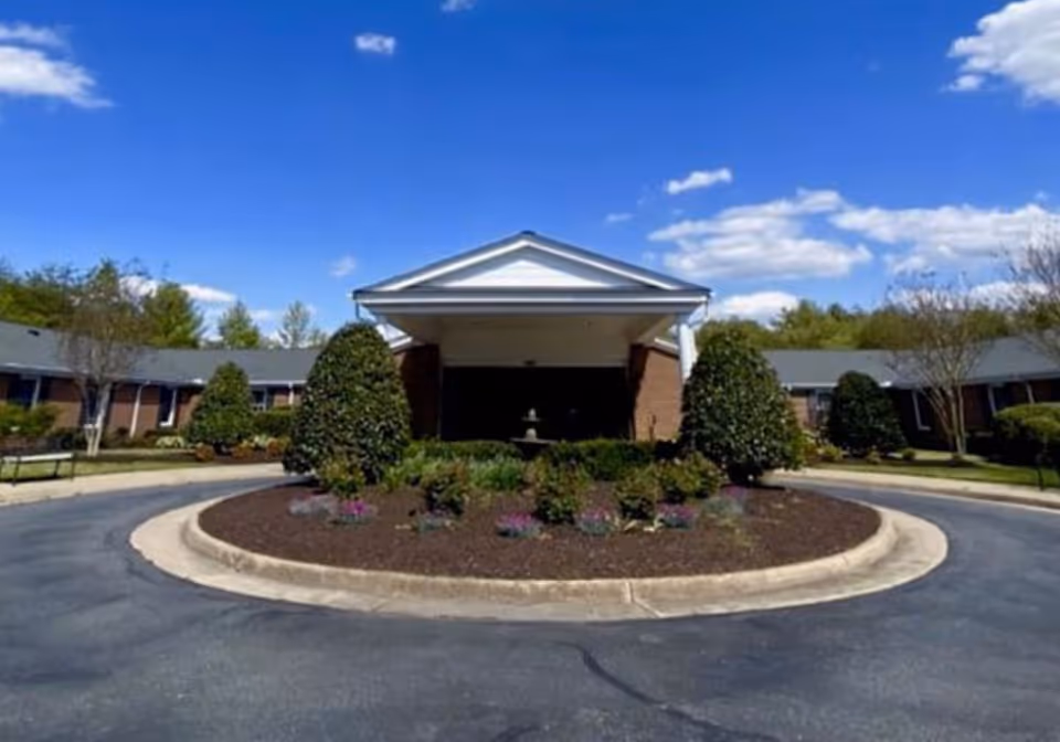Exterior of a senior living facility featuring a circular driveway and landscaped front garden.