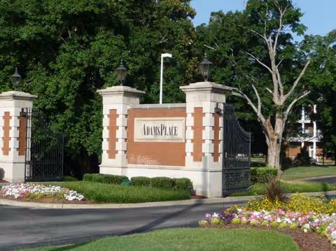 Entrance pillars and a brick sign reading Adams Place at the facility's front entrance.