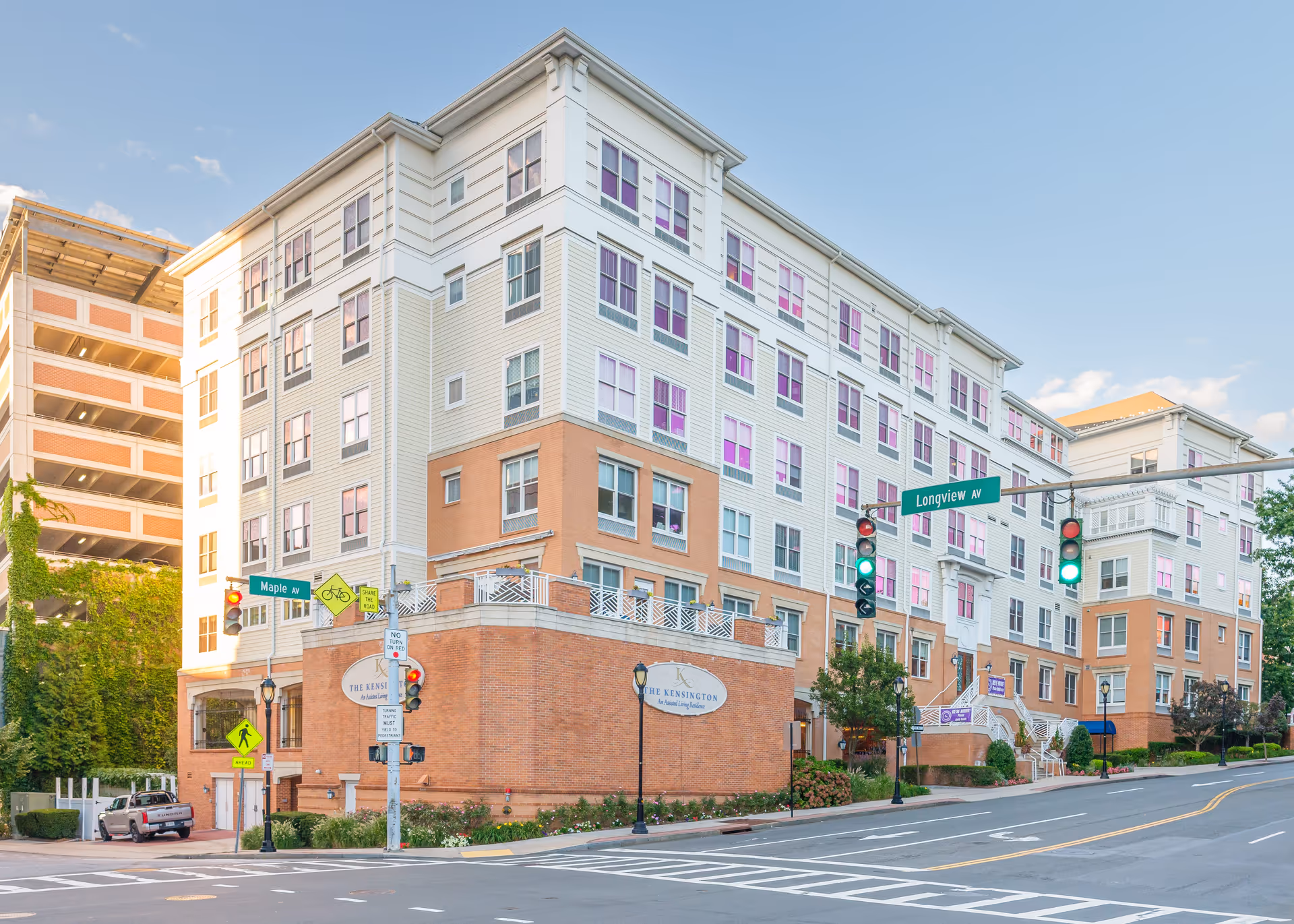 Front exterior of The Kensington White Plains, a multi-story senior living building at a street intersection with traffic lights.