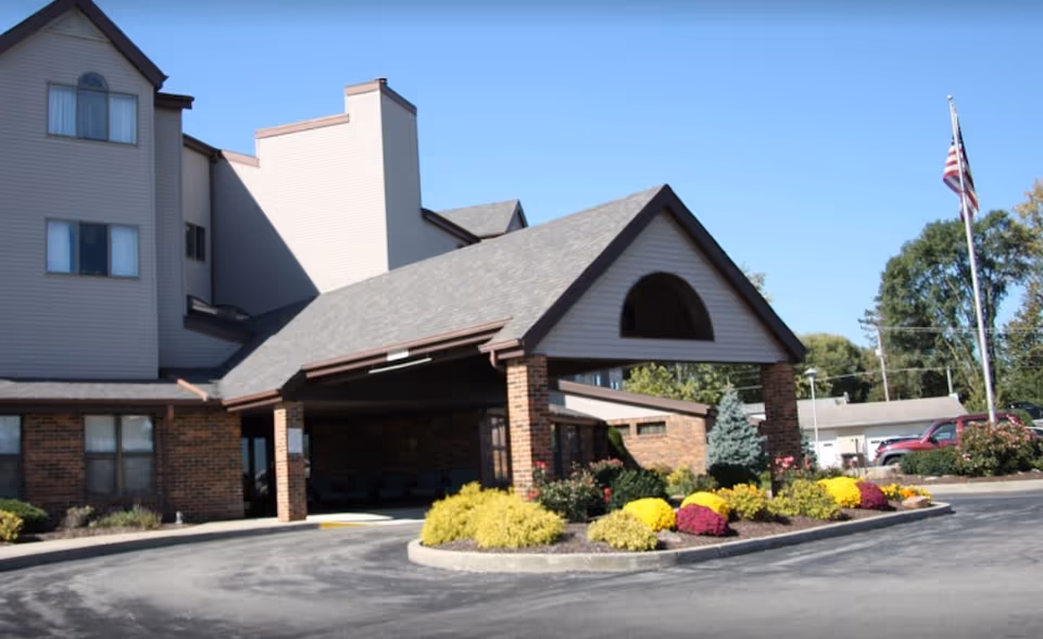 Front view of Golden Years Homestead, Inc. building with entrance arch, flagpole, and landscaping.