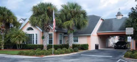 Front exterior view of Brookdale Port Charlotte with palm trees and a covered entrance.
