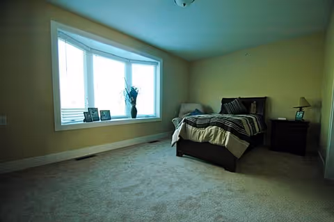 A spacious bedroom with a bed, two nightstands, and a large bay window.