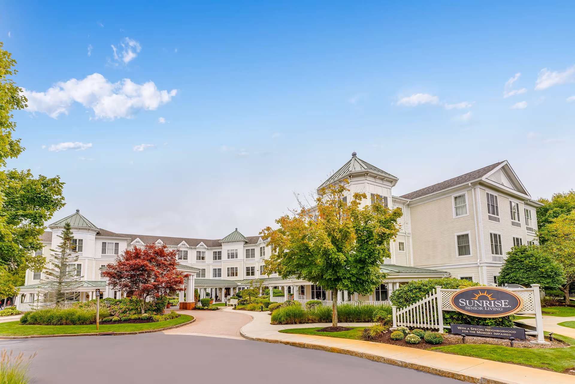 Sunrise of Braintree facility exterior with curved driveway, manicured landscaping, and a sign.