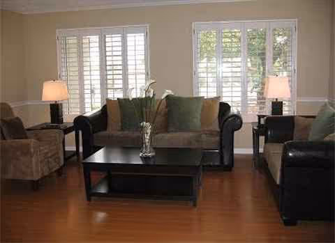 A living room with three sofas, a coffee table, lamps, and large windows.