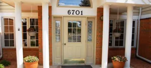 Front entrance of Brookdale Middleton Stonefield with columns, glass doors, and potted plants.