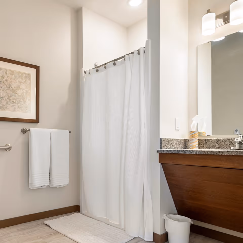 Clean bathroom with a white shower curtain, towel rack, and a vanity with sink and mirror.