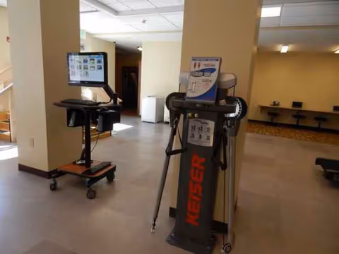 Interior of a senior facility fitness area with a tall Keiser exercise machine and monitor.