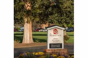 Outdoor view of a sign for Hermitage Richmond, located at 1600 W Broad St, with trees, grass, and a building in the background.