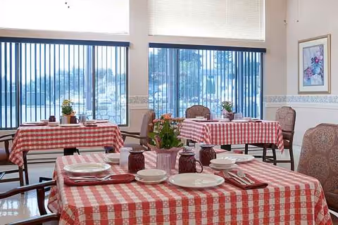 Dining room at Riverside Nursing and Rehab Center with red checkered tablecloths and empty chairs.