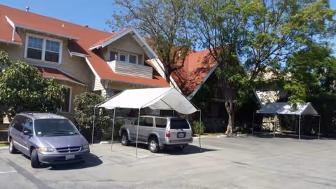 Exterior view of the Discovery 4 facility with parked cars and white canopy tents.
