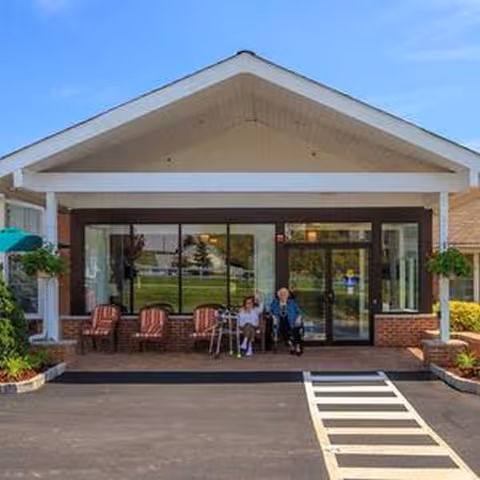 Front entrance of Bentley Assisted Living at Branchville with residents seated on the patio.